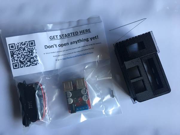 Image of a parts bag containing components for building a Fourby Multifunction USB clock kit, including a QR code sticker, USB module, clock module, retaining screw, and an instruction note.