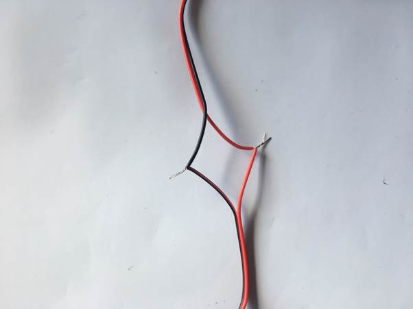 Two stripped electrical wires, one red and one black, lying on a white surface.
