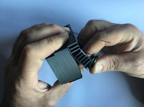 A person holds a 3D printed clock module in both hands, focusing on wire connections and the assembly process.