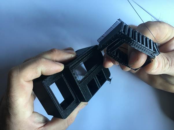 Hands holding two 3D printed parts of a Fourby Multifunction USB clock kit, demonstrating the assembly process.