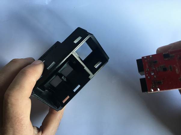Person holding a 3D printed clock casing with an electronic module nearby