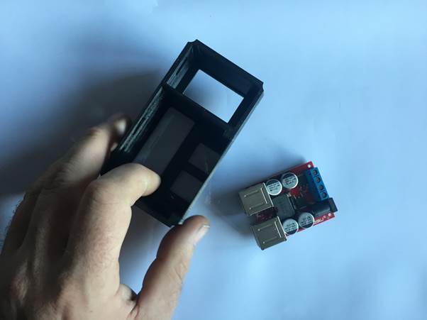 A hand holding a 3D printed case for a multifunction USB clock next to a USB module on a white background.