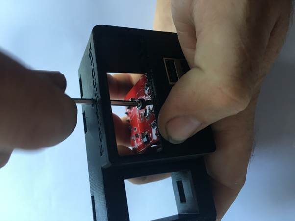 A close-up image of a person using a screwdriver to secure a USB module inside a 3D-printed clock housing.