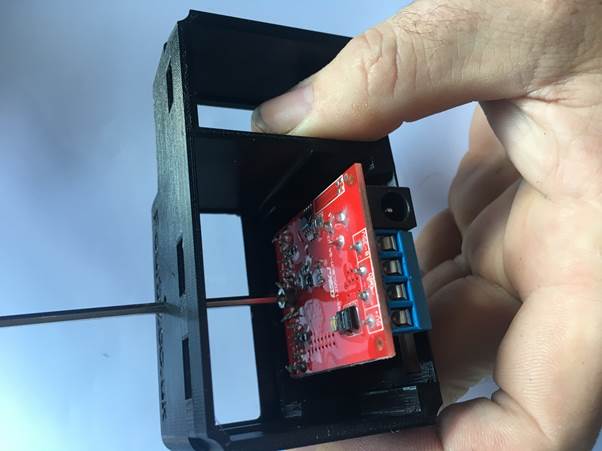 A hand holding a 3D printed clock case with a red circuit board partially inserted inside.