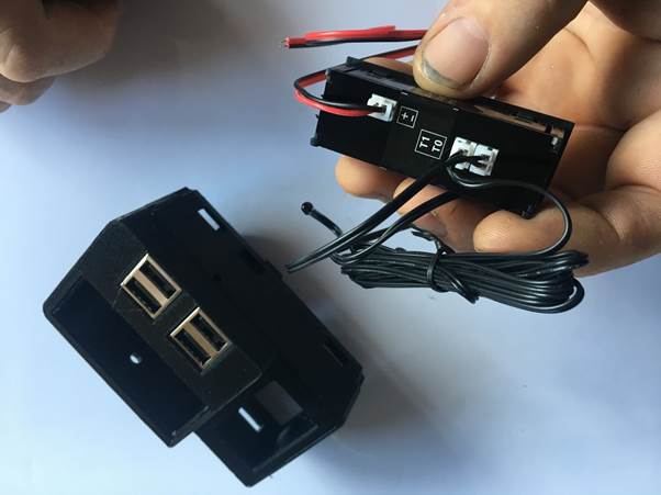 A person holding a Fourby Multifunction USB module showing red and black wires connected, with a USB socket visible on the side.