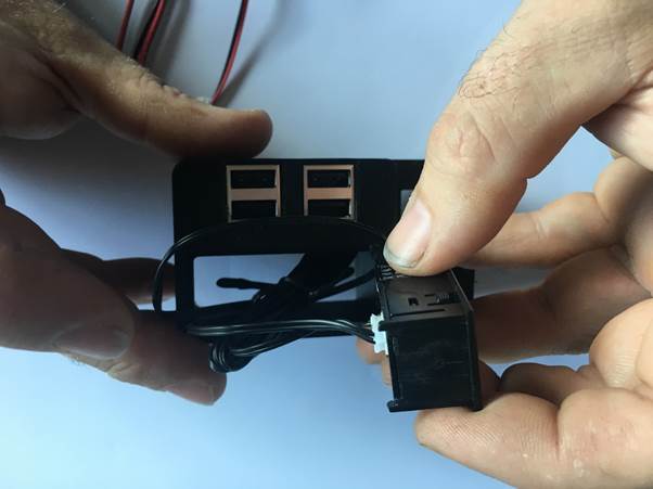 Person holding a USB module with wires attached, displaying two USB ports and a connector.