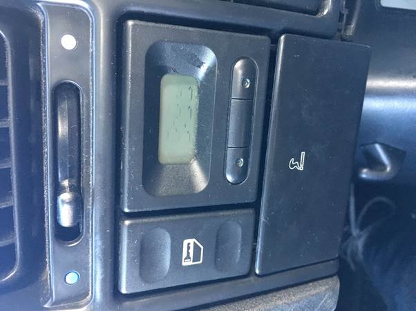 Close-up of a car's dashboard showing the installed Fourby USB clock with visible buttons and a digital display.