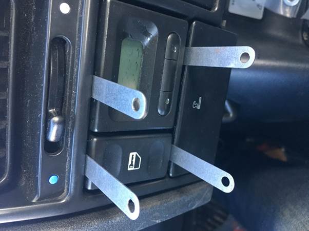 Close-up of a car dashboard with shims inserted to remove the old clock module.