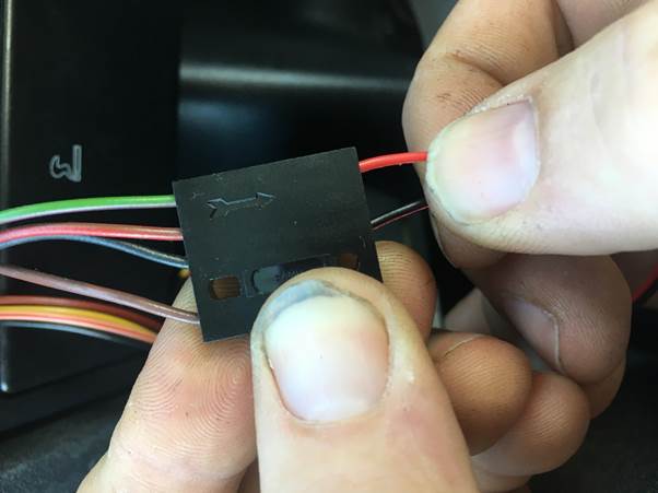 Close-up of a person connecting wires to a black plastic connector block during the Fourby Multifunction Clock kit installation.